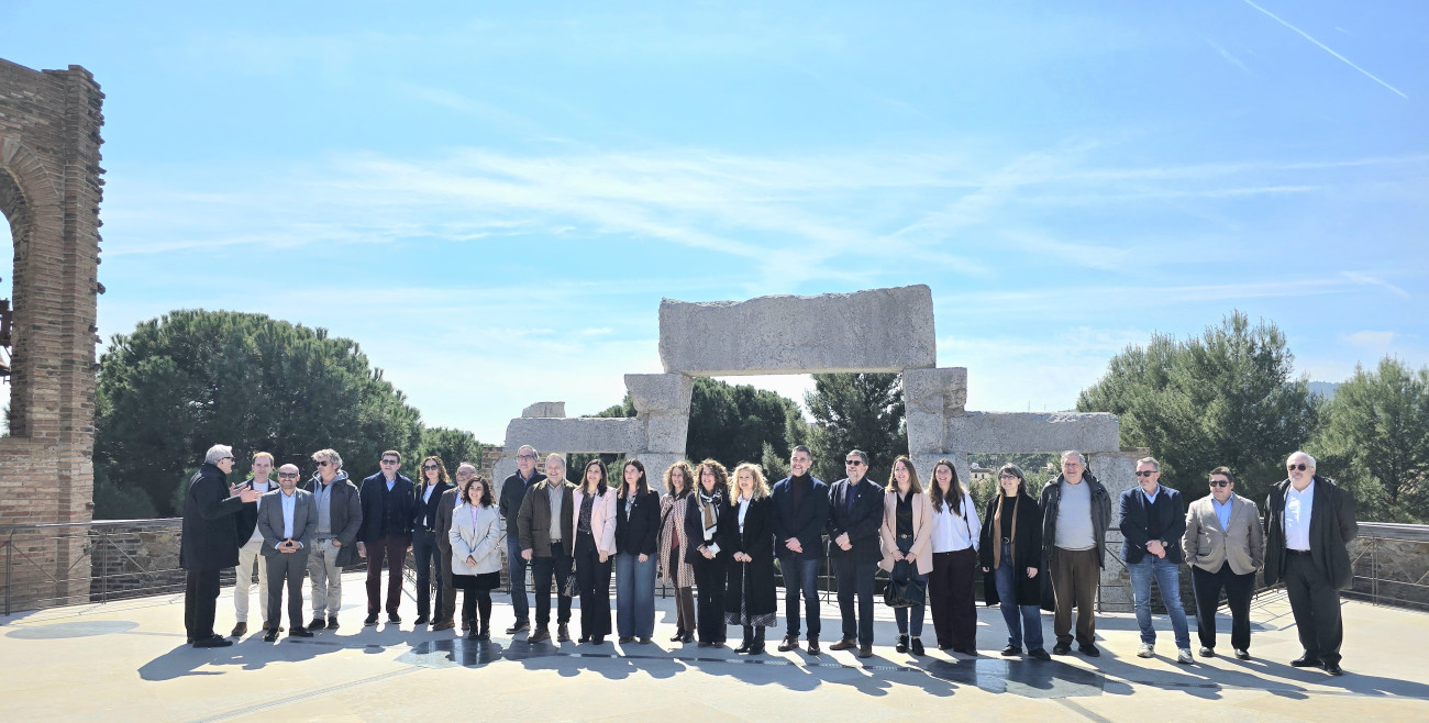 Alcaldesas, concejales y consejeros comarcales posan ante la puerta entrada inacabada de la iglesia de la Colonia Güell, situada sobre la actual Cripta de Gaudí