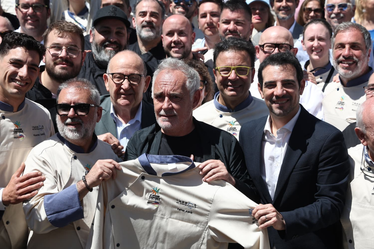 El presidente del Gremio de Hostelería de Castelldefels y el Baix Llobregat, Manuel Ángel Ortíz Chumillas, y el alcalde de la ciudad, Manuel Reyes, entregan la chaquetilla especial de chef de Castelldefels a Ferran Adrià