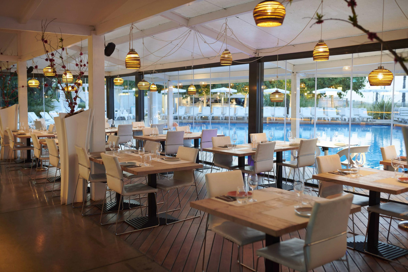 Interior del restaurante con vistas a la piscina y el mar