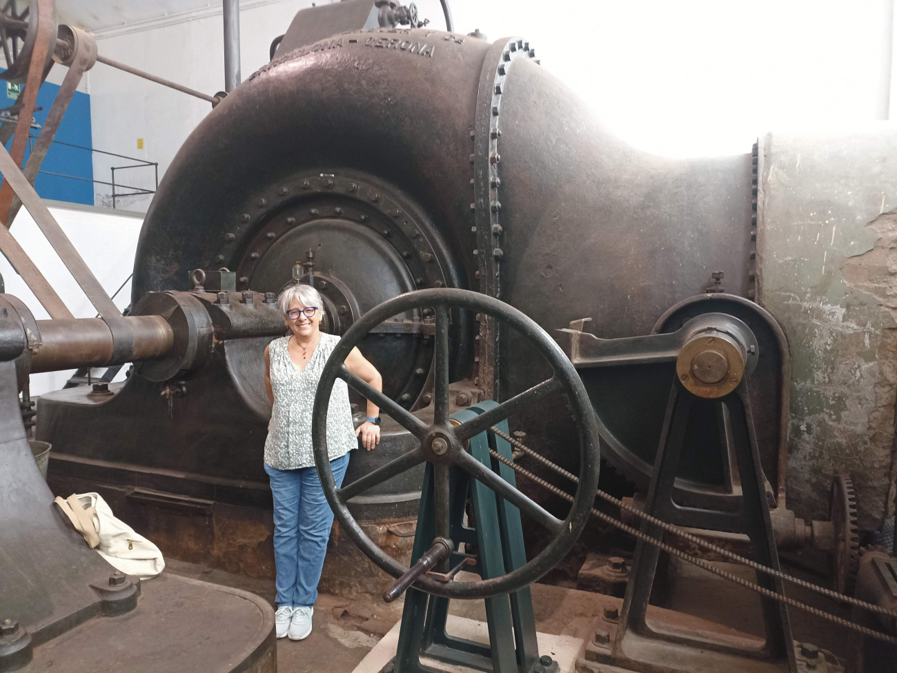 Esther Hachuel al costat de la gran turbina del Museu de la Colònia Sedó d’Esparreguera, que pertany al Museu Nacional de la Ciència i la Tècnica de Catalunya (MNACTEC)