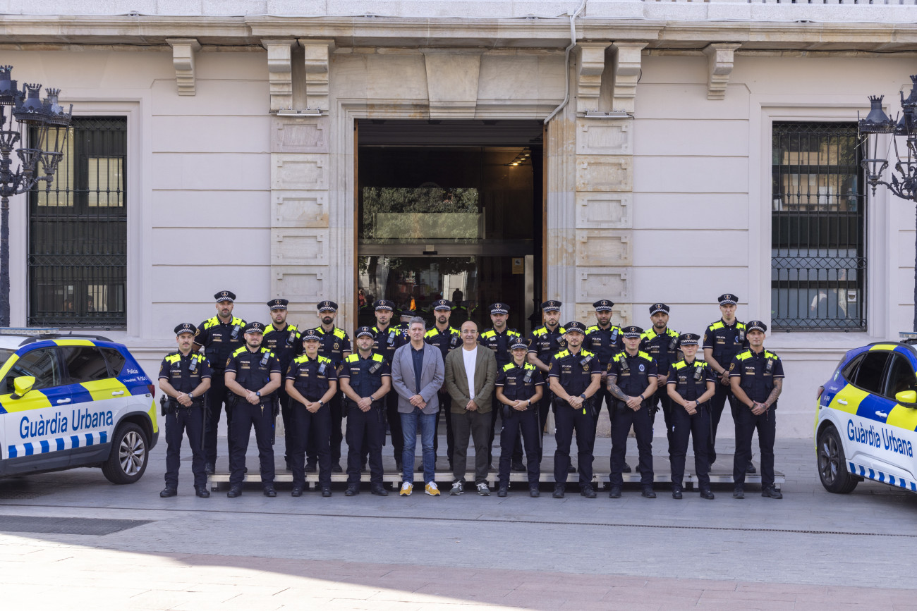 Las autoridades de la ciudad posan en la puerta del Ayuntamiento junto a los nuevos agentes flanqueados por vehículos policiales